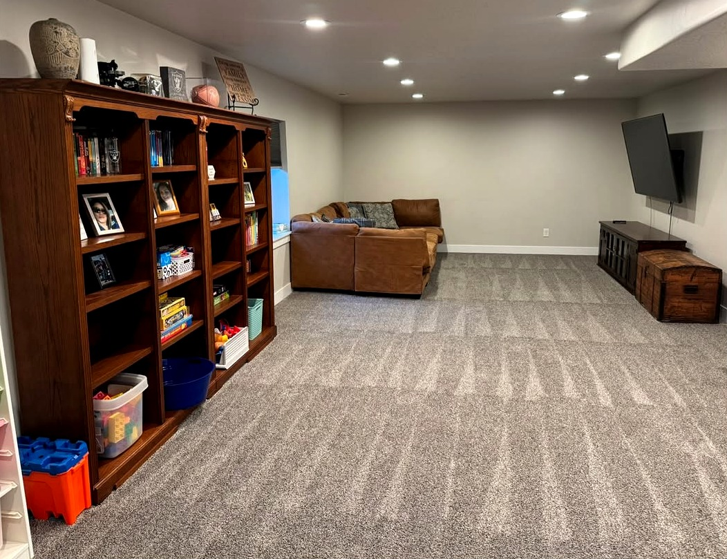 The same basement after a Reset: vacuum lines on the carpet, a tidy sofa, and a clear floor.